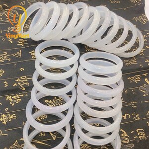May include: A stack of white jade bangles, each with a smooth, polished finish. The bangles are arranged in a circular pattern, creating a visually appealing display.