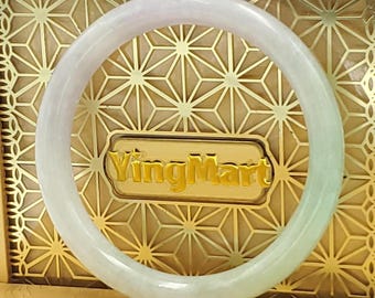 May include: A jade bangle bracelet with a gradient of colors, transitioning from a pale lavender to a soft green. The bracelet is circular and smooth, set against a gold-toned background with the text "YingMart".