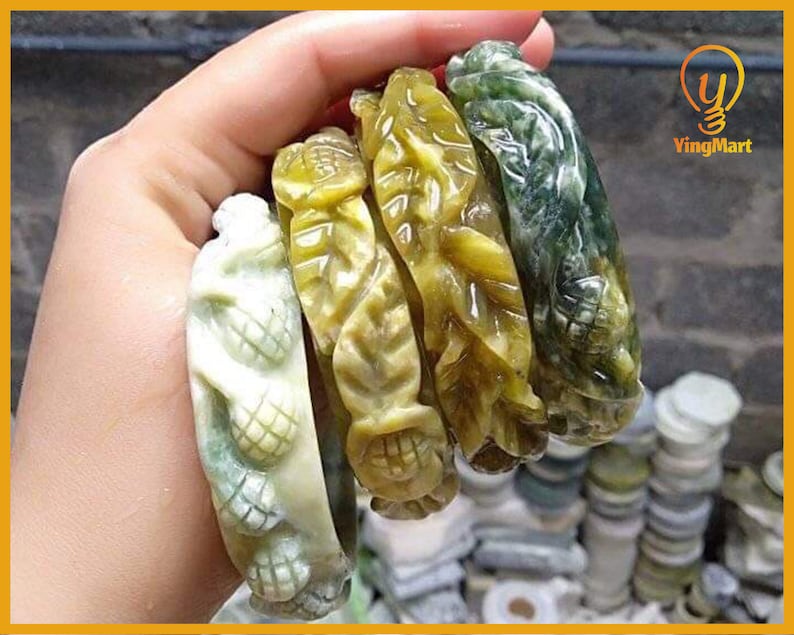 Pode incluir: Cinco pulseiras de jade esculpidas de forma intrincada em tons de verde e amarelo. As pulseiras apresentam desenhos florais e de folhas.