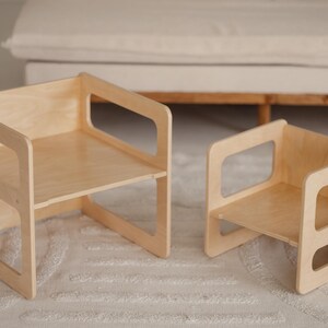 May include: Two wooden children's chairs. The chairs are made of light-colored wood and have a simple, modern design. The larger chair measures approximately 15 inches wide, 15 inches deep, and 15 inches tall. The smaller chair is about 10 inches wide, 10 inches deep, and 10 inches tall.