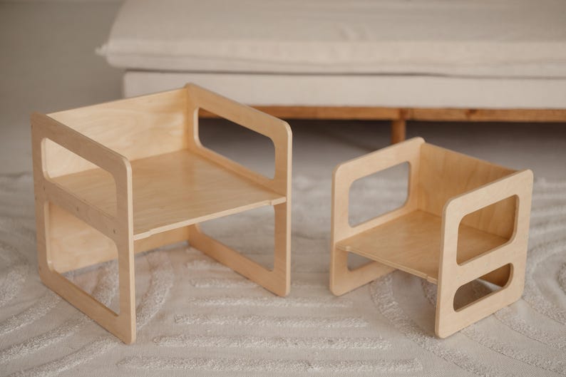 May include: Two wooden children's chairs. The chairs are made of light-colored wood and have a simple, modern design. The larger chair measures approximately 15 inches wide, 15 inches deep, and 15 inches tall. The smaller chair is about 10 inches wide, 10 inches deep, and 10 inches tall.
