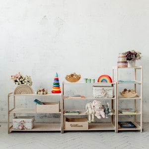 May include: Two white wooden shelves with rainbow wooden arches, a rainbow stacking toy, a wooden rainbow, a basket, and a wooden name sign that says "William".