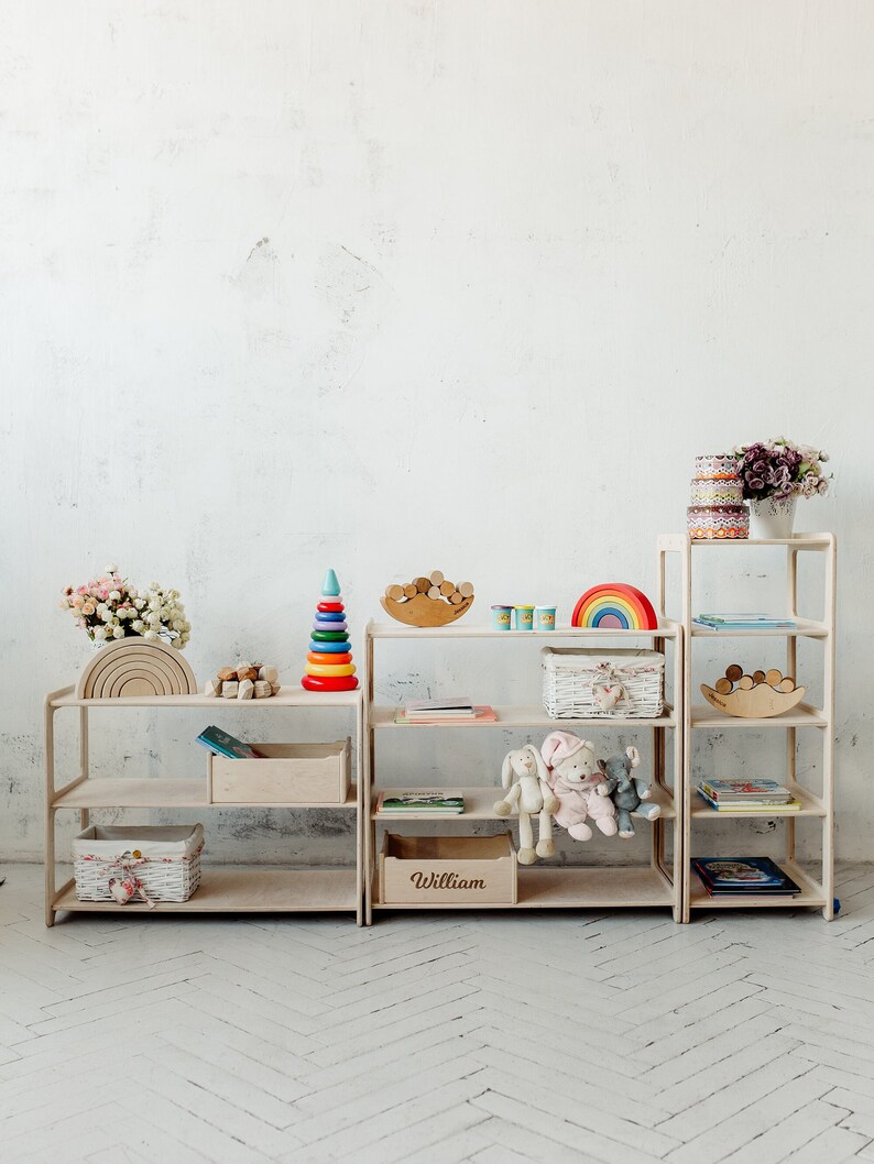 May include: Two white wooden shelves with rainbow wooden arches, a rainbow stacking toy, a wooden rainbow, a basket, and a wooden name sign that says "William".