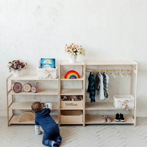 May include: A wooden shelf unit with a rainbow toy, a basket of toys, and a wooden box labeled "William". A child is playing with toys on the floor in front of the shelf.