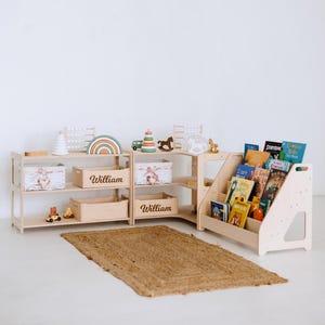May include: A light wood children's bookshelf and storage unit with the name "William" on the storage boxes. The unit holds books, toys, and decorative items. A woven rug is on the floor.