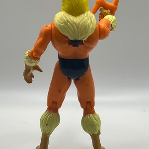 Puede incluir: Una figura de acci&oacute;n vintage de Sabretooth de los X-Men. La figura es naranja y marr&oacute;n con un collar de piel amarillo y un taparrabos negro. La figura sostiene un arma en su mano derecha.