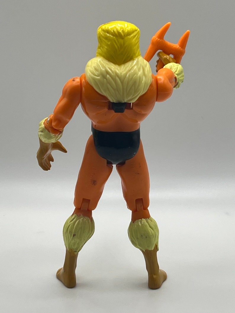 Puede incluir: Una figura de acci&oacute;n vintage de Sabretooth de los X-Men. La figura es naranja y marr&oacute;n con un collar de piel amarillo y un taparrabos negro. La figura sostiene un arma en su mano derecha.