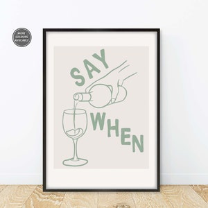 Pode incluir: Uma impress&atilde;o emoldurada com um fundo bege claro e texto verde que diz "SAY WHEN". Uma m&atilde;o est&aacute; a verter vinho de uma garrafa para um copo.