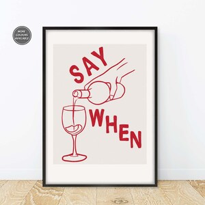 Pode incluir: Uma impress&atilde;o emoldurada com fundo branco e texto vermelho que diz "SAY WHEN". Uma m&atilde;o est&aacute; a verter vinho de uma garrafa para um copo.