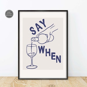 Pode incluir: Uma impress&atilde;o emoldurada branca com uma ilustra&ccedil;&atilde;o azul de uma m&atilde;o despejando vinho de uma garrafa em um copo. O texto "SAY WHEN" est&aacute; escrito em azul abaixo da ilustra&ccedil;&atilde;o.