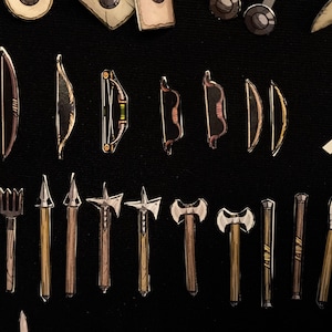 May include: An assortment of illustrated miniature weapons, including bows, axes, spears, and knives, are arranged on a black background. The weapons vary in design, with some featuring intricate details and contrasting colors.