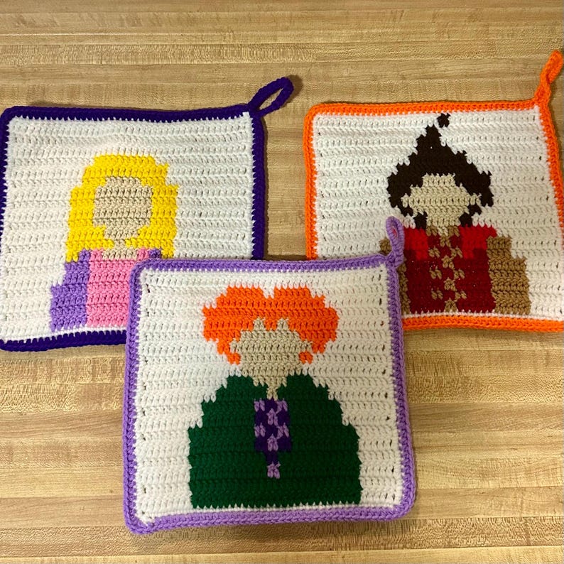 May include: Three crocheted pot holders featuring cartoon characters with different coloured hair and clothing. The characters are Harry Potter, Ron Weasley, and Hermione Granger.