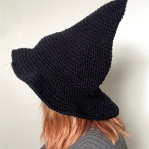 May include: A black crocheted witch hat with a pointed crown and a wide brim.