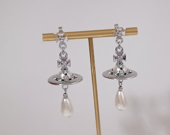 Vivienne Westwood- Boucles d'oreilles en plaqué argent avec des perles synthétiques, des cristaux et saturne.