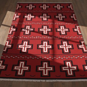 May include: A rectangular area rug featuring a vibrant red background with a repeating pattern of black and white crosses. The design includes horizontal rows of dashed lines between the crosses and a white fringed edge at the bottom end.