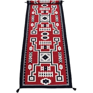 Peut inclure: Un tapis de couloir rectangulaire avec un motif géométrique. Le tapis présente un champ central rouge avec des formes géométriques blanches, noires et grises. La bordure est noire et le tapis a des glands à chaque extrémité.