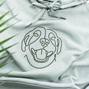 May include: A light green hooded sweatshirt with a single-line embroidered design of a dog's face.