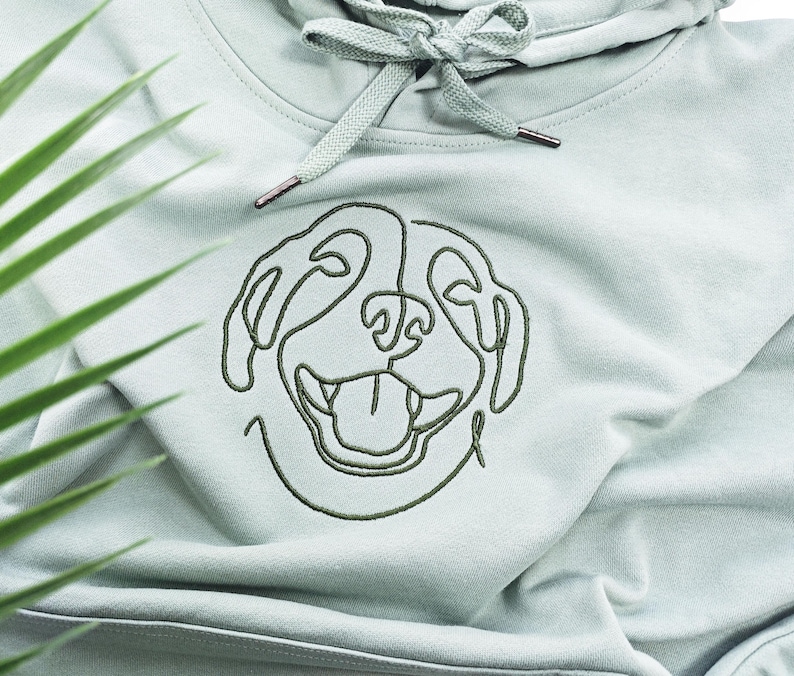 May include: A light green hooded sweatshirt with a single-line embroidered design of a dog's face.