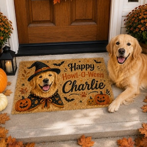 Puede incluir: Un felpudo rectangular de fibra de coco beige con un golden retriever que lleva un sombrero de bruja y una capa, dos calabazas de Halloween, murciélagos negros y el texto "Happy Howl-O-Ween Charlie" impreso en letras negras y naranjas.