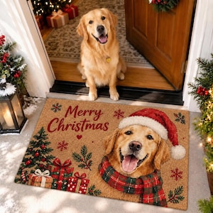 Peut inclure: Un paillasson rectangulaire en fibre de coco beige avec l'inscription Merry Christmas en lettres rouges. Le motif représente un golden retriever portant un bonnet de Père Noël et une écharpe à carreaux rouges et verts, avec un sapin et des cadeaux.