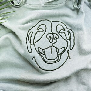 May include: A light green hoodie with a black embroidered outline of a dog's face.