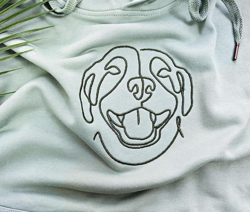 May include: A light green hoodie with a black embroidered outline of a dog's face.