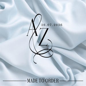 Può includere: Design elegante con le lettere "AZ" intrecciate, accompagnate dalla data "26.07.2026" in stile minimalista. Il testo "MADE TO ORDER" è in basso, su uno sfondo di tessuto azzurro.