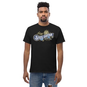 A 30-something, tall, serious-looking black male wearing a black t-shirt. The t-shirt has a vintage design (like 1800's soap advertisement) that says "Steel Guitar, breakin' hearts since 1890s"
