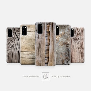 May include: Five different phone cases featuring a wood grain design. The cases are all clear and display the phone's camera lens. The cases are arranged in a row from left to right.