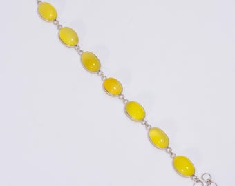 May include: A silver bracelet with yellow oval-shaped gemstones. The bracelet has a lobster clasp closure and a decorative chain link design.