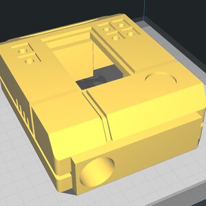 May include: A yellow 3D printed plastic box with a hollow center and multiple circular holes on the top and sides.