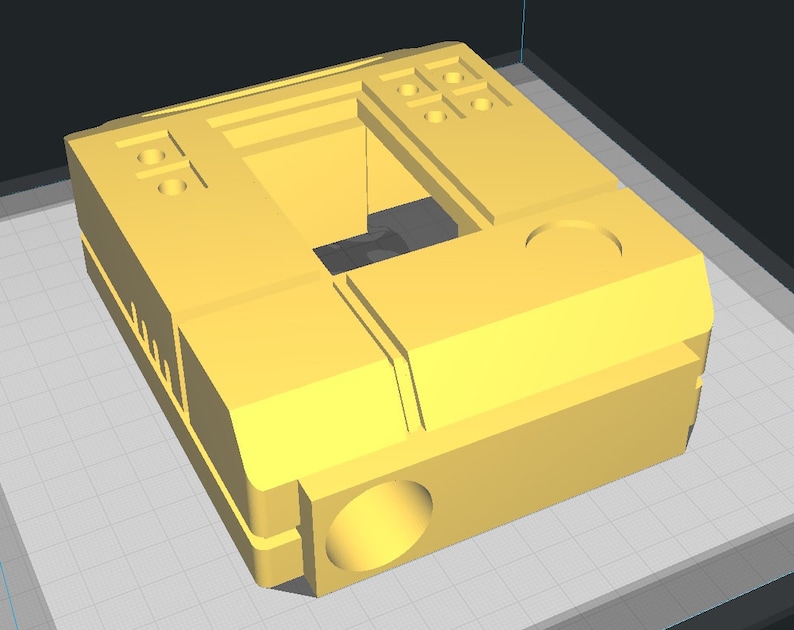May include: A yellow 3D printed plastic box with a hollow center and multiple circular holes on the top and sides.