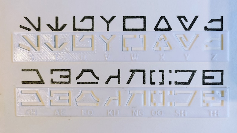 Peut inclure: Une feuille de plastique blanche avec des symboles noirs imprim&eacute;s dessus. Les symboles sont dispos&eacute;s en rang&eacute;es et en colonnes. Les symboles sont de formes et de tailles diff&eacute;rentes. Les symboles sont &eacute;tiquet&eacute;s avec les lettres de l'alphabet.