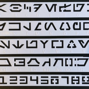 Peut inclure: Pochoirs en plastique blanc avec des symboles noirs pour l'alphabet et les chiffres. Les symboles sont pour l'alphabet Aurebesh, un alphabet fictif utilis&eacute; dans l'univers Star Wars. Les pochoirs sont dispos&eacute;s en rang&eacute;es, chaque rang&eacute;e contenant un ensemble diff&eacute;rent de symboles. La premi&egrave;re rang&eacute;e contient les lettres A &agrave; H, la deuxi&egrave;me rang&eacute;e contient les lettres I &agrave; R, la troisi&egrave;me rang&eacute;e contient les lettres S &agrave; Z, la quatri&egrave;me rang&eacute;e contient les lettres CH, AL, EO, KH, NG, OO, SH et TH, et la cinqui&egrave;me rang&eacute;e contient les chiffres 1 &agrave; 9.
