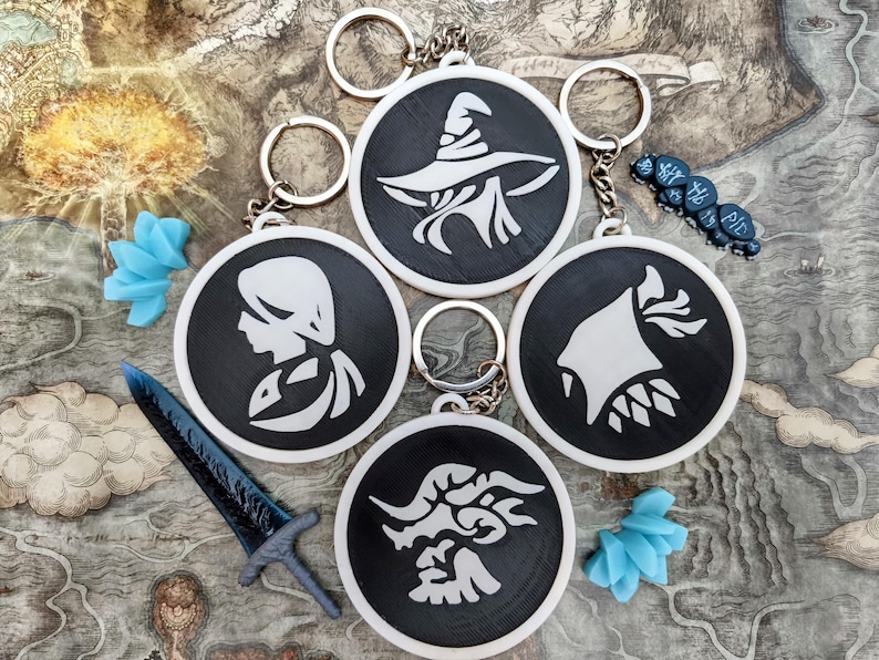 May include: A collection of black and white keychains with various fantasy-themed designs, including a wizard, a profile, and a creature. The keychains are round and have silver key rings. Also included are a blue sword and blue decorative flowers.