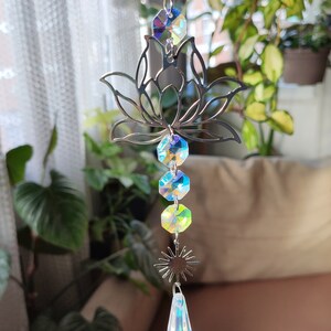 May include: A silver metal lotus flower suncatcher with iridescent crystal beads and a teardrop-shaped crystal hanging from the bottom.