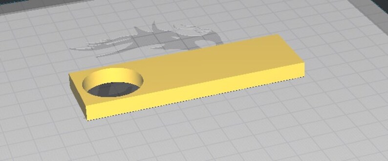 May include: A yellow plastic rectangular block with a round hole in the center. The block is on a gray grid background.