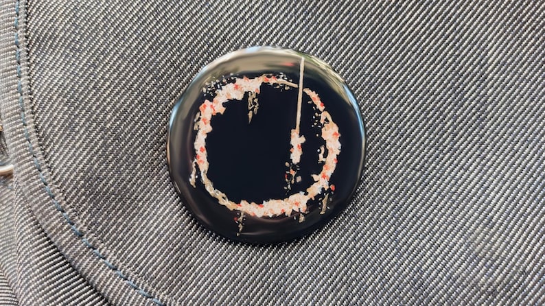 May include: A black and white button with a red and white circle design. The circle has a white line through it.