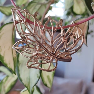May include: A gold leaf-shaped hair clip with a delicate, intricate design. The clip is made of metal and has a spring-loaded mechanism.