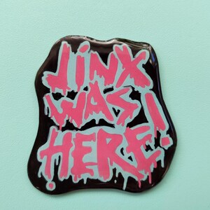 May include: A black sticker with pink and white dripping paint that says "Jinx was here!"