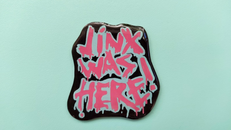 May include: A black sticker with pink and white dripping paint that says "Jinx was here!"
