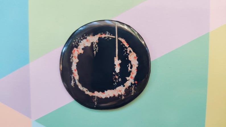 May include: A black button with a red and white circle design. The circle is a stylized power button symbol.