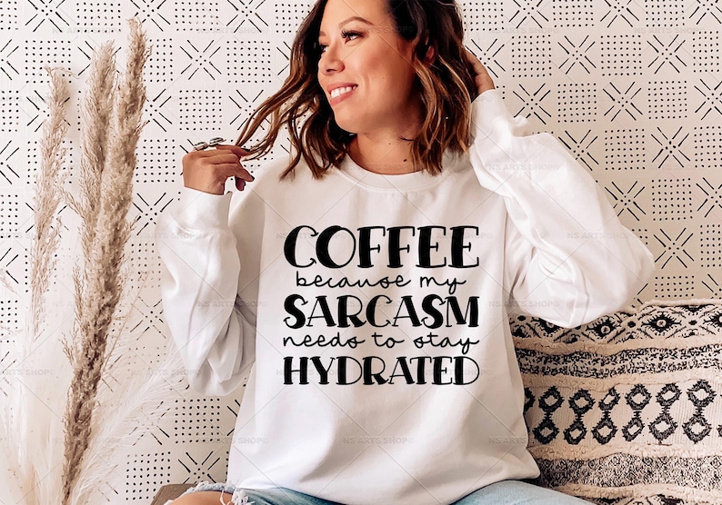 Puede incluir: Sudadera blanca de manga larga con texto negro que dice "Coffee because my sarcasm needs to stay hydrated."