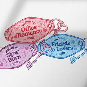 May include: Three motel-style key fobs with heart-shaped key rings. The key fobs are in pink, purple, and blue, each with a different phrase: "Office Romance", "Slow Burn", and "Friends to Lovers". The key fobs have a vintage aesthetic.