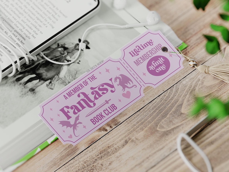 May include: A lavender-colored bookmark with the text "A MEMBER OF THE Fantasy BOOK CLUB" and "Lifetime MEMBERSHIP admit one." The bookmark features a dragon, sword, and heart design. A tassel and earbuds are also visible.