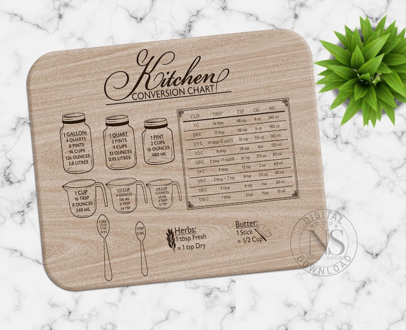May include: A wooden cutting board with a kitchen conversion chart engraved on it. The chart includes measurements for cups, tablespoons, teaspoons, ounces, and milliliters. It also includes conversions for gallons, quarts, pints, and ounces. The board has a brown wood grain finish.