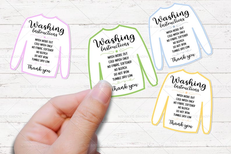 May include: A hand holding four sweater-shaped stickers with washing instructions. Each sticker has a different colored outline: pink, green, blue, and yellow. The text on each sticker reads "Washing Instructions" and laundry care guidelines.