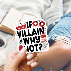 Puede incluir: Una pegatina blanca con el texto "IF VILLAIN WHY HOT?" e ilustraciones de una m&aacute;scara roja, esposas, labios, una calavera, un chile y un libro. La pegatina la sostiene una persona con esmalte de u&ntilde;as blanco.
