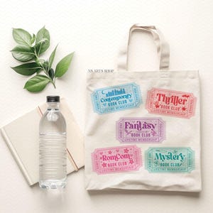 Puede incluir: Una bolsa de mano blanca con dise&ntilde;os de boletos de club de lectura coloridos. Los boletos est&aacute;n etiquetados como "Contemporary", "Thriller", "Fantasy", "RomCom" y "Mystery". Una botella de agua y un cuaderno est&aacute;n junto a la bolsa.