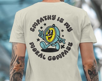 May include: A light beige t-shirt with a cartoon clock face wearing a blue hat and walking. The text "Empathy is my moral compass" is written in a circle around the clock face.
